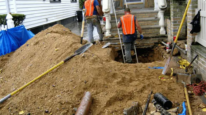 Contractors performing foundation protection and exterior drainage excavation near residential home steps in Mobile, AL